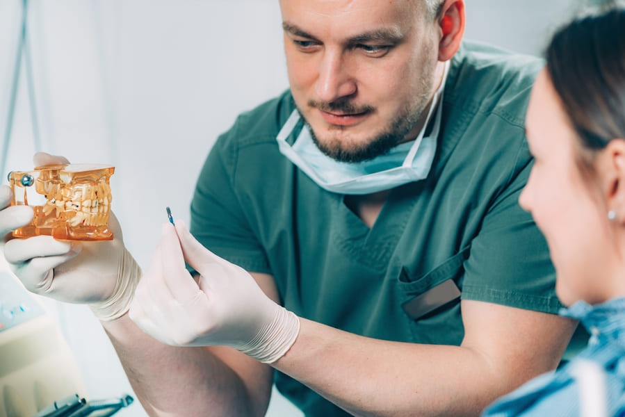 Dentysta pokazujący pacjentce procedurę wszczepiania implantów